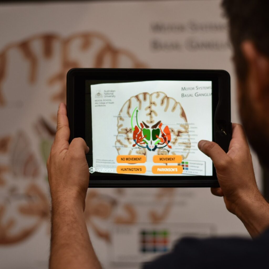 A person holds an iPad over a poster to show the augmented reality features
