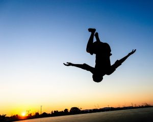 A sillouette of a person flipping upside down.