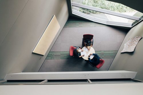 An aerial view of two students sitting with a lecturer at a table.